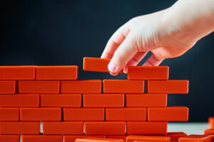 Hand puts last brick on wall. Concept of construction and building